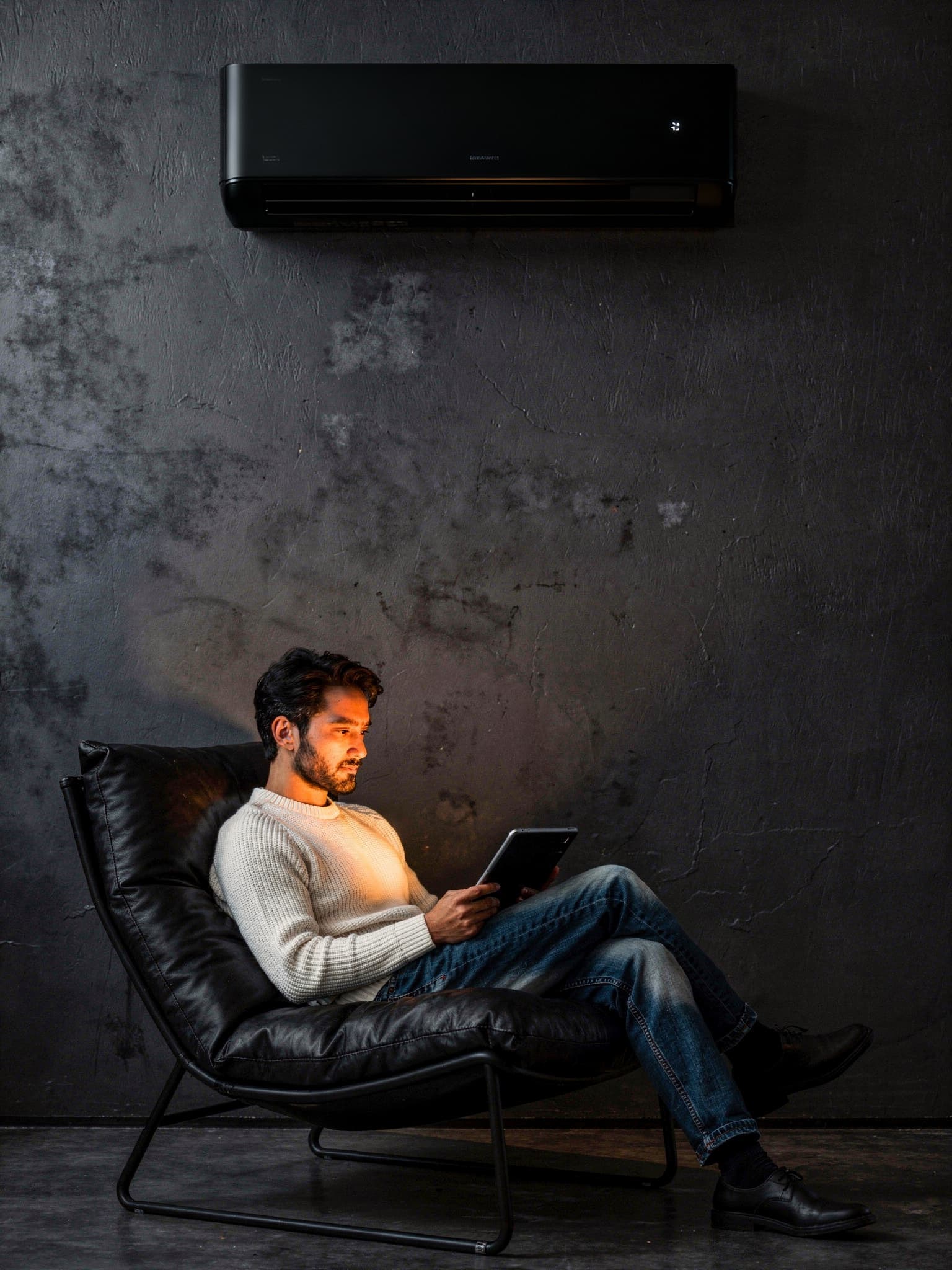 Hombre relajado en sillón moderno con aire acondicionado negro de diseño